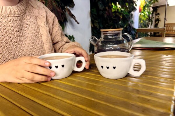 Deux mains autour de tasses de café sur une table, moment de dialogue en couple